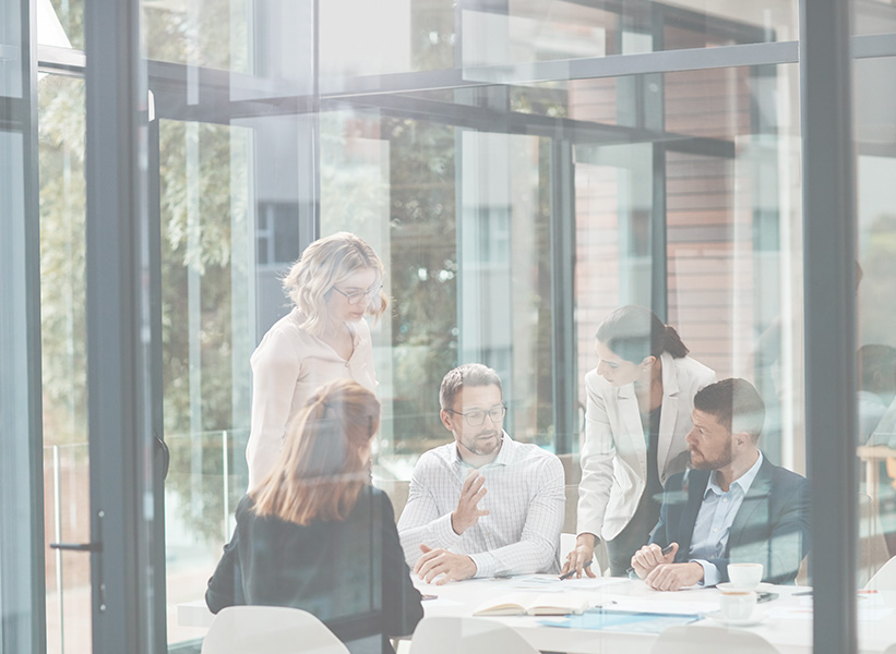 Equipo de trabajo colaborando en una reunión sobre estrategias con inteligencia artificial, en una sala de vidrio